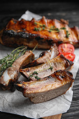 Tasty grilled ribs on black wooden table, closeup