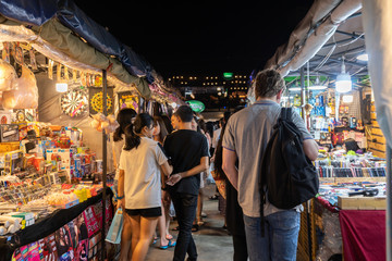 Fototapeta na wymiar Tourist and locals walking and shopping at Rachada Night train market (Talad Rot Fai). market with plenty of shops with colorful canvas roofs at night in Bangkok, Thailand