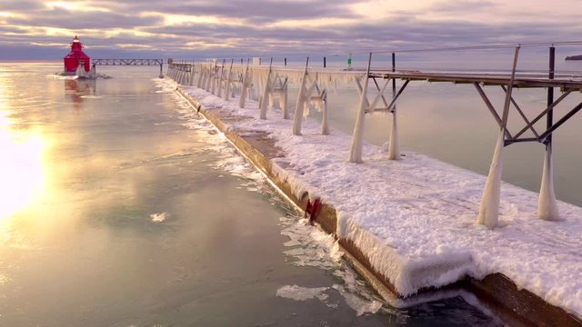 Moving drone view of ice covered pier and catwalk, with fascinating ice shove phenomenon happening along pier edge.
