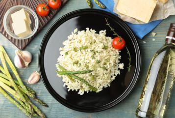 Delicious risotto with asparagus served on blue wooden table, flat lay