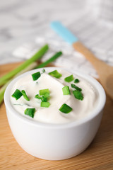 Fresh sour cream with onion on wooden board, closeup