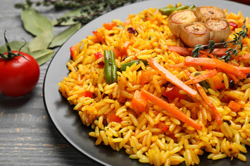 Tasty rice pilaf with vegetables on grey wooden table, closeup