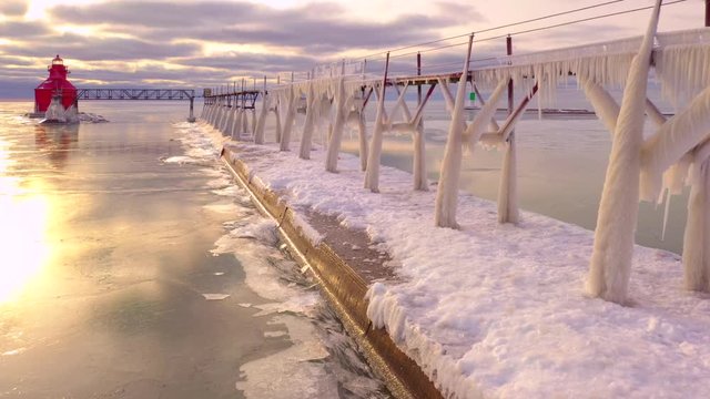 Moving drone view of ice covered pier and catwalk, with fascinating ice shove phenomenon happening along pier edge.