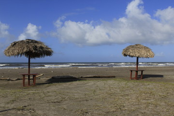 Fototapeta na wymiar Table under a palm umbrella on the beach shore under a palm umbrella on the beach shore
