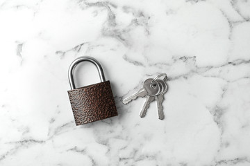 Steel padlock and keys on white marble background, top view. Safety concept