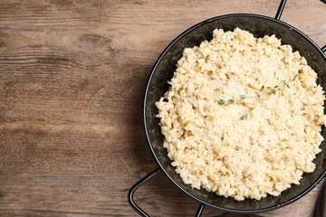 Delicious risotto with cheese on wooden table, top view. Space for text