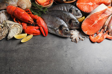 Fresh fish and different seafood on grey table, flat lay. Space for text