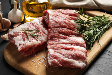 Raw ribs with rosemary and salt on black table, closeup