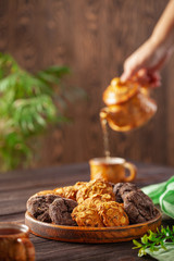 Set of different cookies in a plate and tea on a wooden background.