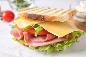 Tasty sandwich with ham on white marble table, closeup