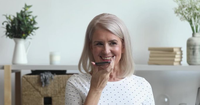 Smiling senior woman activate virtual digital voice assistant on phone