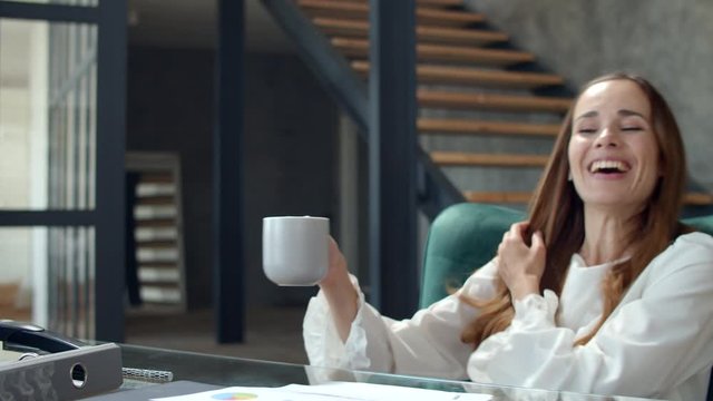 Portrait of happy woman feeling satisfied on workplace. Lady drinking tea.