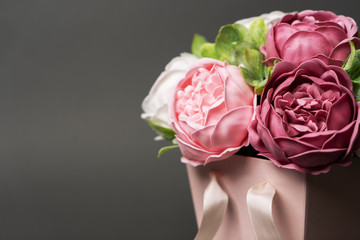 Flowers in bloom: Bouquet of lilac and pink peonies in a pink square box on a gray background.
