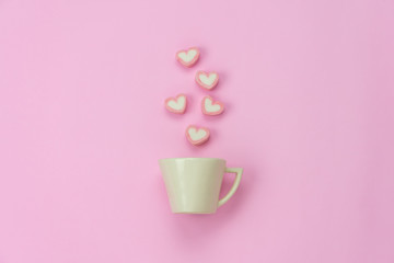 Table top view aerial image of sign valentine's day background concept.Flat lay arrangement white coffee cup with steam heart shape on modern pink paper at home office desk studio.Pastel tone design.