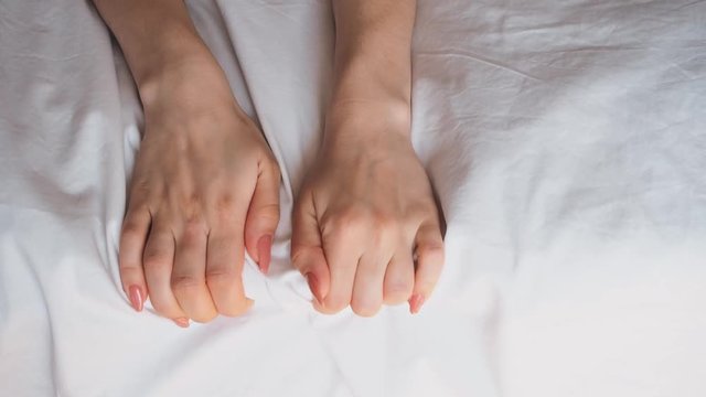 girl's hands on the bed in the bedroom against the white sheet