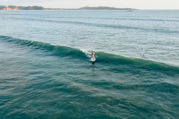 Surfer girl surfing on longboard at Weligama beach, Sri Lanka