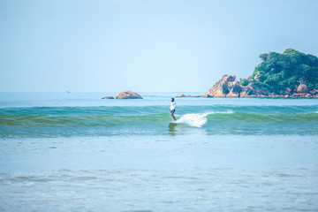 Surfer riding wave on longboard at Weligama beach, Sri Lanka