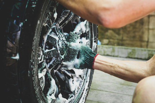 People cleaning car with sponge at automobile wheels wash