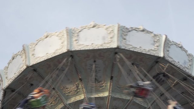 4k clip of people experiencing centripetal forces while riding a flying spinning swing at a amusement park in Barcelona