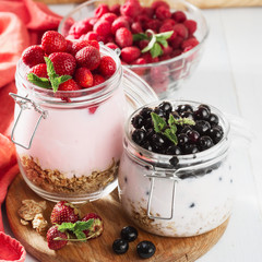 Glass jar of healthy yogurt with fresh berries, oats and mint on wooden table. healthy breakfast concept