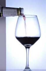 Sirviendo vino en copa de vidrio con fondo blanco