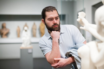 Man looking at stone architectural elements in historical museum hall