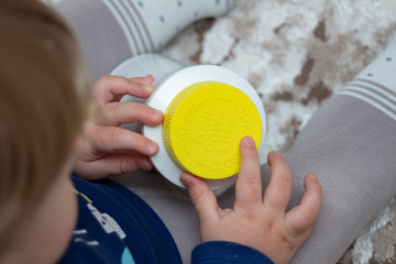 A child independently tries to open a plastic bottle of medicine, close-up. Child-resistant,...