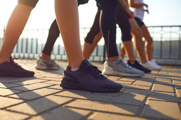 Legs of a group of sports people runners on a track in a park.