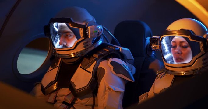 Male and female astronauts navigating spaceship