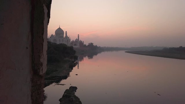 view of taj mahal sunset pull in through an old arch of stone marble, colorful sky, india