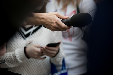 Fototapeta premium Hand with microphone doing an interview for the media, selective focus