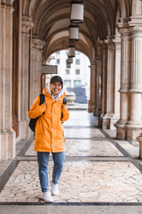 woman tourist walking with backpack in yellow raincoat city tourism