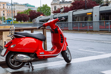 red stylish scooter at city street after rain