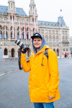 man in yellow raincoat with big dslr camera at city square