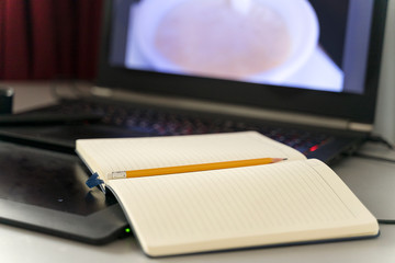 a diary and a pencil lie on a laptop