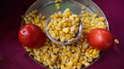 Boiled corn served with red tomatoes.