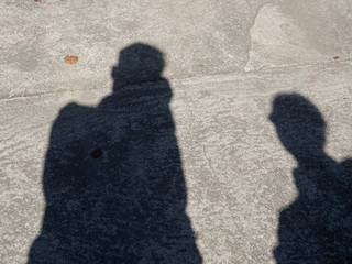 Shadows of men and women on the concrete road