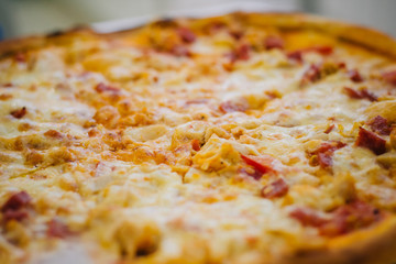 Round appetizing pizza with sausage and tomatoes. Fast food on blurred background