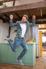 Fototapeta premium Joyful and energetic man jumping in his kitchen