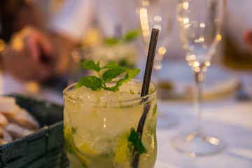 Delicious mojito at the El Jardin restaurant in Alcossebre, Castellon, Spain. July 2019. Original shaped glass with a plastic straw to drink it (not eco friendly). White table.