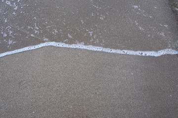 Close up of sandy beach with small waves, abstract background