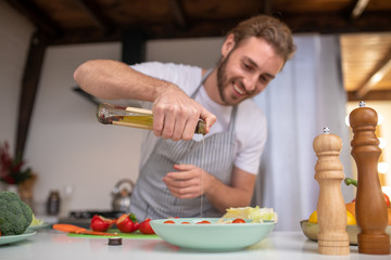 Concentrated cook putting some oil into a salad