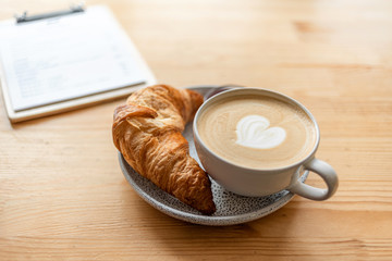 coffee shop menu and croissant and cup of cappuccino