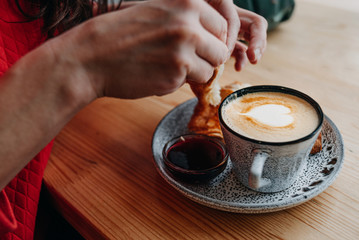 man eating a croissant and a cup of cappuccino