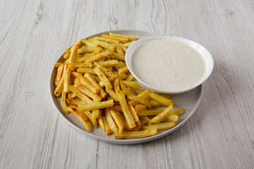 Homemade Crispy Ranch Fries on a gray plate on a white wooden background, low angle view. Close-up.