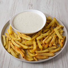 Homemade Crispy Ranch Fries on a gray plate on a white wooden surface, side view. Close-up.