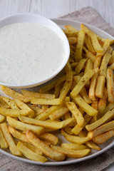 Homemade Crispy Ranch Fries on a gray plate on a white wooden surface, low angle view. Close-up.