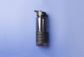 black plastic sport bottle lying blue background