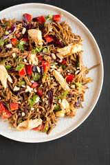 Homemade Spicy Chicken Soba Noodle Salad on a gray plate on a black surface, top view. Flat lay, overhead, from above.