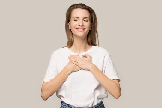 Happy grateful woman hold hands at chest feeling thankful